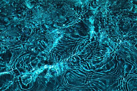 Closeup of rough water surface texture with splashes and bubbles in deep green emerald color. Trendy...