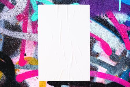 Closeup of colorful messy painted urban wall texture with wrinkled glued poster template . Modern mockup for design presentation. Creative urban city background. の写真素材