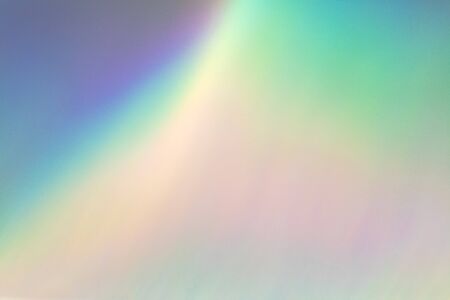 Blurred rainbow light refraction texture overlay effect for photo and mockups. Organic drop diagonal holographic flare on a white wall. Shadows for natural light effectsの写真素材