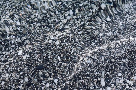 transparent clear calm water surface with small grey pebbles sea bottom texture