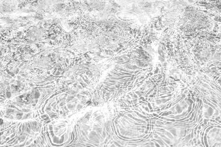 Closeup of desaturated transparent clear calm water surface texture with splashes and bubbles....