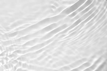 Closeup of desaturated transparent clear calm water surface texture with splashes and bubbles. Trendy abstract nature background. White-grey water waves in sunlight.の写真素材