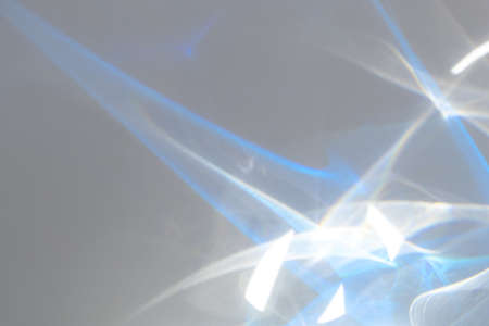 Blurred rainbow light refraction texture overlay effect for photo and mockups. Organic drop diagonal holographic flare on a white wall. Shadows for natural light effectsの写真素材