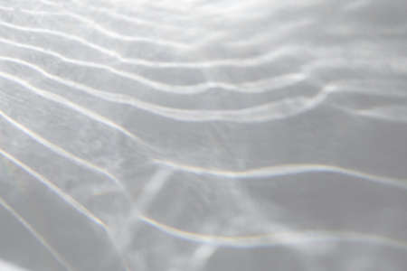 Water texture overlay effect for photo and mockups. Organic drop diagonal shadow and light caustic effect on a white wall. Shadows for natural light effectsの写真素材