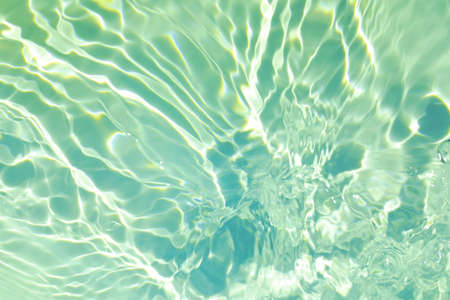 Closeup of mint green transparent clear calm water surface texture with splashes and bubbles. Trendy abstract summer nature background. Mint colored waves in sunlight.の写真素材