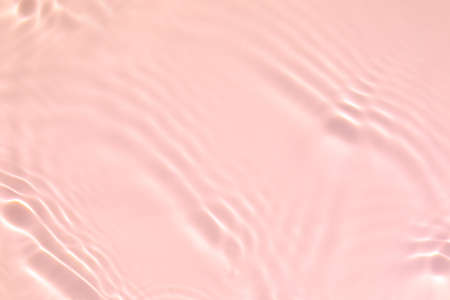 Closeup of pink transparent clear calm water surface texture with splashes and bubbles. Trendy abstract summer nature background. Coral colored waves in sunlight.の写真素材
