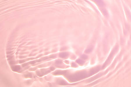 Closeup of pink transparent clear calm water surface texture with splashes and bubbles. Trendy abstract summer nature background. Coral colored waves in sunlight.の写真素材