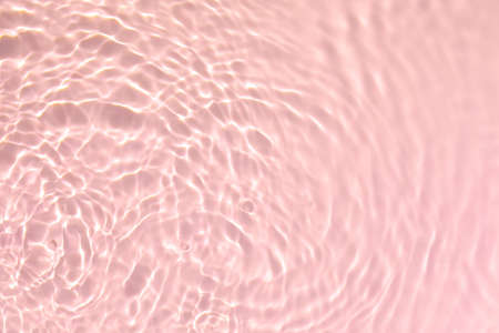 Closeup of pink transparent clear calm water surface texture with splashes and bubbles. Trendy abstract summer nature background. Coral colored waves in sunlight.の写真素材