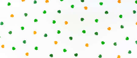 banner with green orange and white shamrock confetti sparse on white background