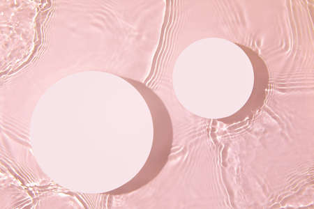 Two empty white circle podiums on transparent pink water backgroundの写真素材