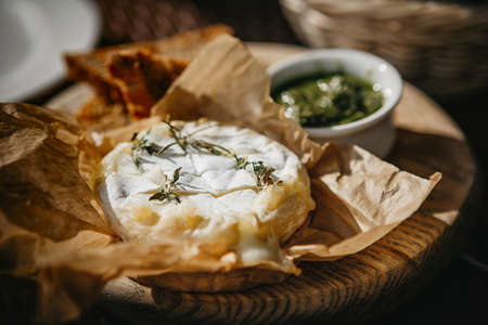 Oven baked camembert cheese with rosemary and pesto sauceの写真素材