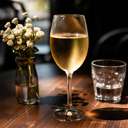 glass of cold white wine back-lit by sunlightの写真素材