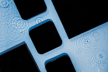 Abstract black geometric figures composition on transparent blue clear water