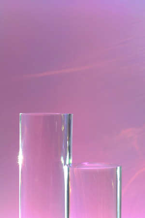 two clear glass cylinder podiums on pastel pink backgroundの写真素材