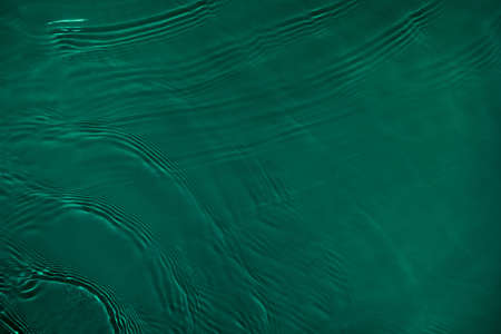 transparent dark green colored clear calm water surface textureの写真素材