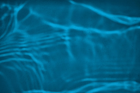 Shadow and light water caustic effect on blue concrete wall