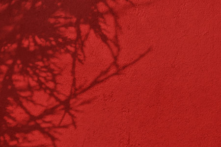 Shadow of leaves on red concrete wall texture background