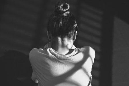 Photo of a girl sitting on the floor in a closed dark room.の写真素材