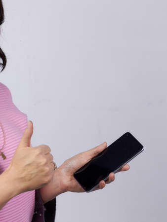 A businessman girl holds a smartphone in her hands, a photo on a white background.の写真素材