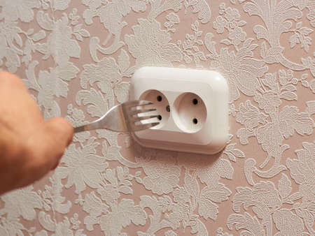 A person inserting a table plug into an electrical outlet is dangerous, it is life-threatening.の写真素材