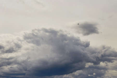 A small sports plane flies through the sky with clouds.の写真素材