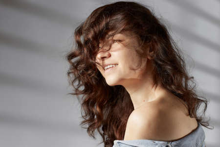 A beautiful and cool girl with dark curly hair on a gray background.