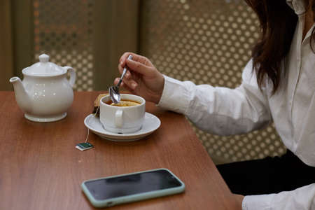 Delicious tea party. A girl sitting at a table drinking tea from a cup.の写真素材