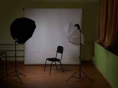 The chair is standing next to the white one, she is next to the lighting equipment.の写真素材