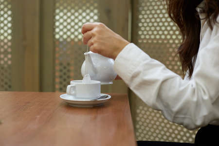 The girl pours tea into her mug for morning breakfast.の写真素材