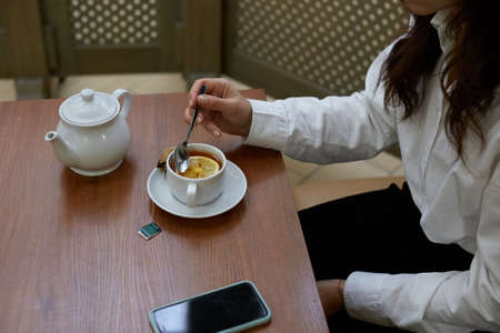 A woman drinks tea from a cup after lunch, she has a tea party.