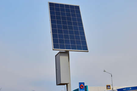A solar battery on a pole against a blue sky energizes a street lamp.の写真素材