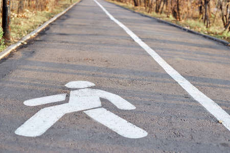 A pedestrian path with a painted sign in white paint on the asphalt.の写真素材