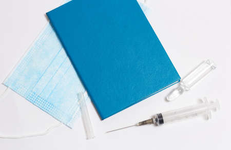 in the photo, a medical mask, a syringe for injections, a vaccination passport. The concept of vaccination of the population, a pandemicの写真素材
