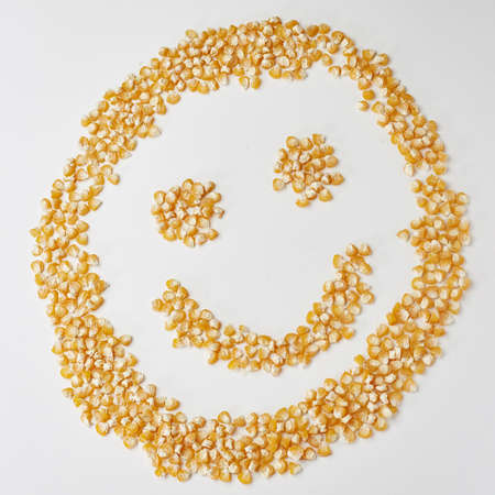 Smiley face made from corn seeds on a white background, the emotion is cheerful