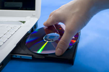 hand and disk drive, dvd-rom, white laptopの写真素材