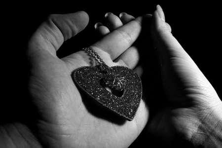 Heart with necklace in man hand like a declaration in love to womanの写真素材