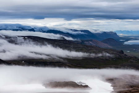Clouds flowing low in the beautiful Iceland mountain landscape - view from the slope of Snaefellsjokull volcano. Hiking in Saefellsnes peninsula in western Iceland.の写真素材
