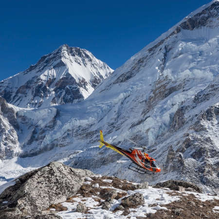 EVEREST BASE CAMP TREK/NEPAL - OCTOBER 31, 2015: Rescue helicopter in high Himalayan mountains. Red rescue helicopter flying near Everest summit on a clear sunny day. Mountain rescue service.のeditorial素材