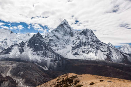 Beautiful view of Ama Dablam mountain summit on the famous Everest Base Camp trek in Himalayas, Nepal. Snowy mountain summit on a cloudy day. Panoramic mountain summit landscape.の写真素材