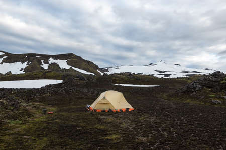 Wild camping in Iceland lava field with white cap of Snaefellsjokull volcano summit on the horizon. Hiking in beautiful Saefellsnes peninsula, western Iceland.の写真素材