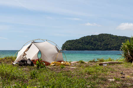 Camping on a beach of an uninhabited island. Tropical jungles landscape, blue sea water and paradise beach camping. Exotic location for camping on beach.の写真素材