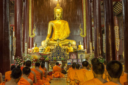 CHIANG MAI, THAILAND - NOVEMBER 04, 2014: Buddhist monks meditating in front of the Buddha image in Phan Tao Temple. Golden Buddha statue and buddhist monks praying.のeditorial素材