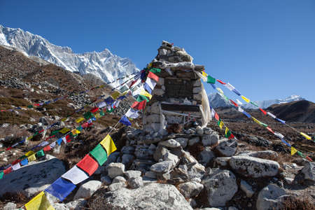 NEPAL - OCTOBER 24, 2015: Buddhist prayer flags on a chorten memorial to honor the great polish climbers: Jerzy Kukuczka, Rafal Cholda and Cheslaw Jakiel with Lhotse mountain on the background.のeditorial素材