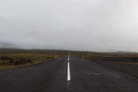 Iceland road leading straight to the horizon filled with clouds. Empty straight road line in rural Icelandic landscape on a cloudy summer day. Road on Saefellsnes peninsula in western Iceland.の写真素材