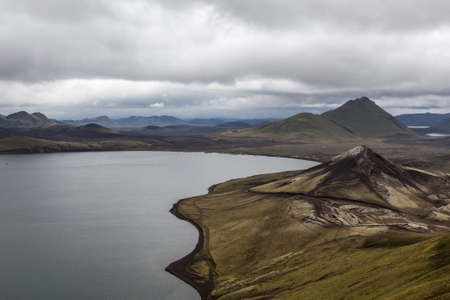 Dramatic Iceland scenery with big lake and green mountains covered with thick icelandic moss.の写真素材