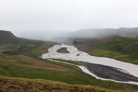 Iceland river landscape on a gray misty day. River surrounded by big cliffs. Volcanic rock...