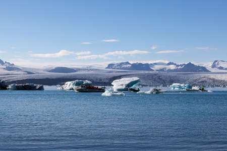 Tourists on the sightseing boat trip in iceland. Scattered melting icebergs in Jokulsarlon glacier...