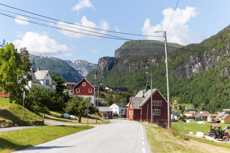 Norwegian village in mountains. Road in Norway on sunny day along the fjord.の写真素材