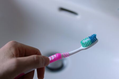 Hand holding Toothbrush in a Faucet. Dental Care concept.の写真素材