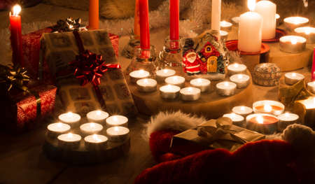 Christmas still life with candles of different size and shape, decorative round wood, souvenir Santa Claus clay house, gift boxes, christmas tree toy.  Closeup view.の写真素材